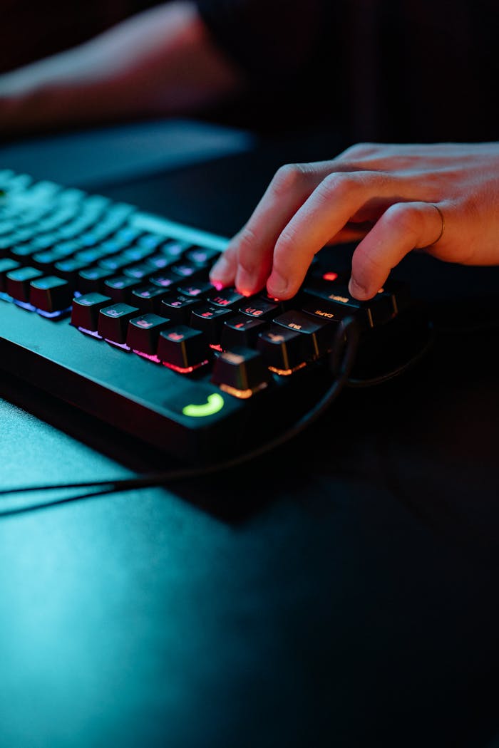 About A close-up shot of a hand typing on a brightly lit RGB mechanical keyboard, emphasizing modern technology.