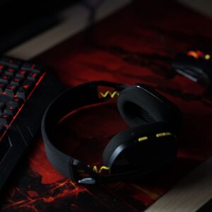 A sleek gaming setup featuring a backlit keyboard, wireless headphones, and a gaming mouse on a vibrant desk pad.